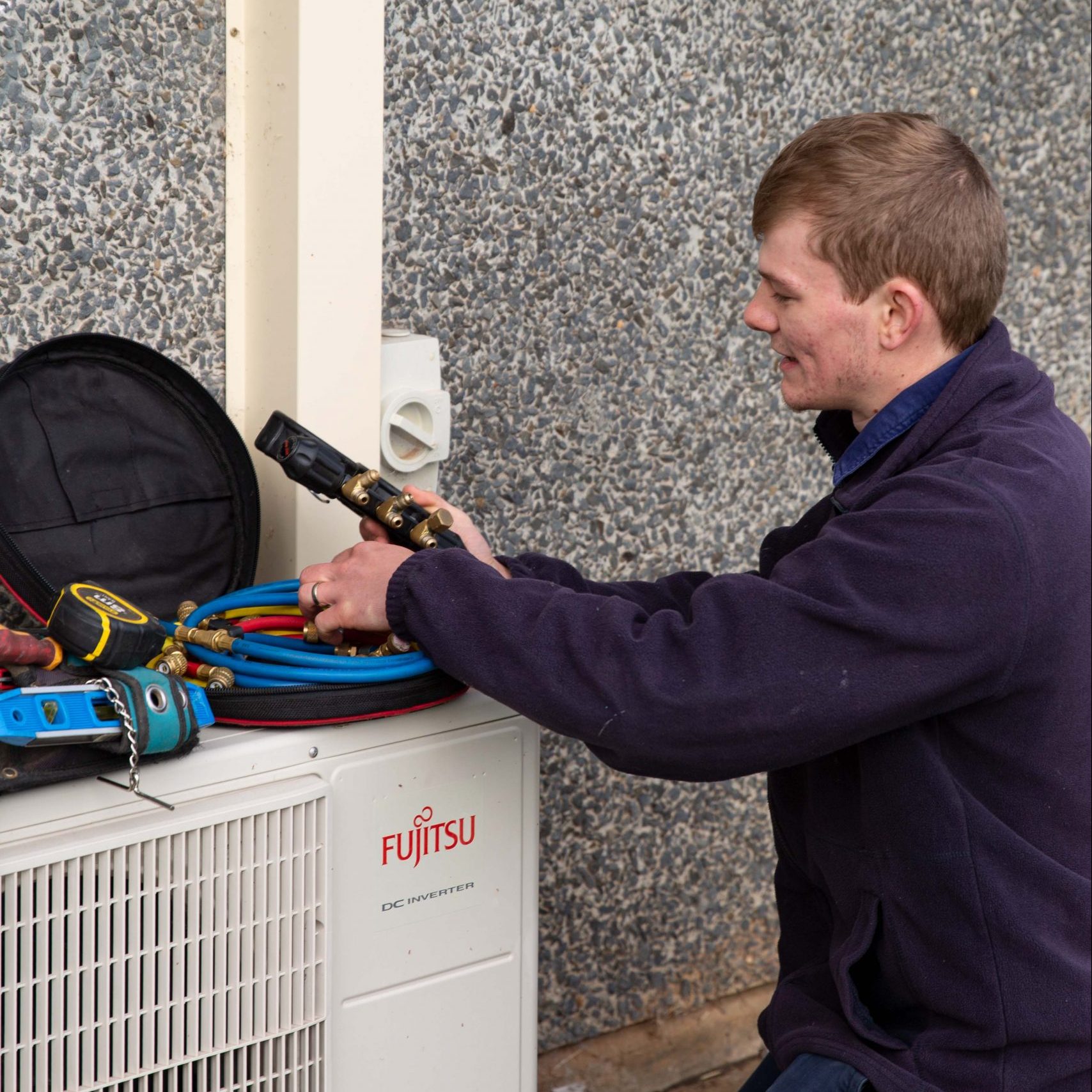 Orange Electrical Works technician inspecting a Fujitsu air conditioner
